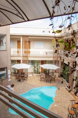 a pool in a courtyard with tables and chairs at Casagrande Olímpia Hotel in Olímpia