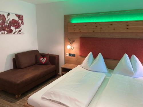 a bedroom with a bed and a couch at Hotel Garni Siegmundshof - inclusive Joker Card im Sommer in Saalbach Hinterglemm