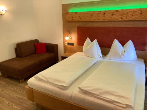 a hotel room with a bed and a chair at Hotel Garni Siegmundshof - inclusive Joker Card im Sommer in Saalbach Hinterglemm