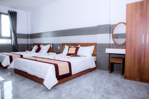 a bedroom with two beds and a mirror and a sink at Trường Phúc Vinh Hotel in Phan Thiet