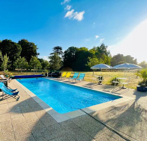 - une piscine avec des chaises et des parasols bleus dans l'établissement Chambres d'hôtes Château de La Croix Chemin, à Saint-Léger-des-Prés