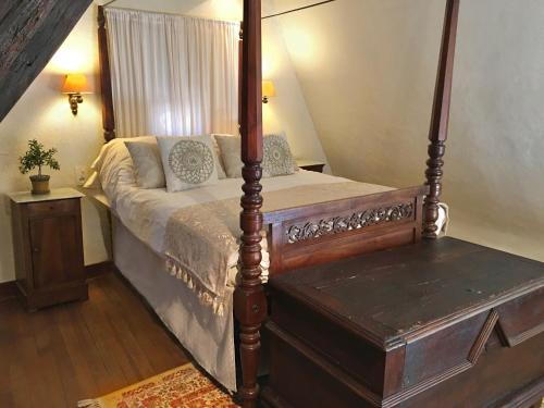 a bedroom with a four poster bed and a table at La Petite Maison in Beynac-et-Cazenac