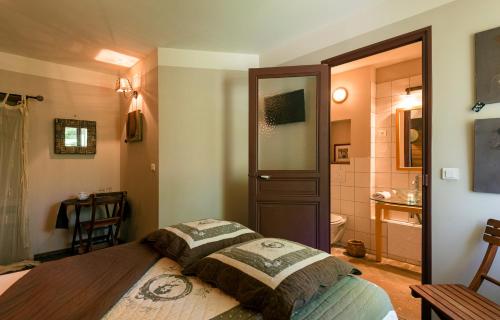 a bedroom with a bed and a bathroom at Hôtel Mas Vidau Porte des Alpilles in Saint-Étienne-du-Grès