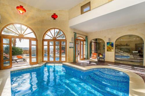 a swimming pool in a house with a large room with windows at The Hamlet 3 Holiday Home in Għasri