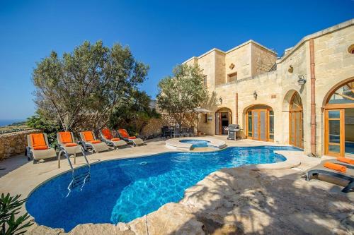 a swimming pool with chairs and a house at The Hamlet 3 Holiday Home in Għasri