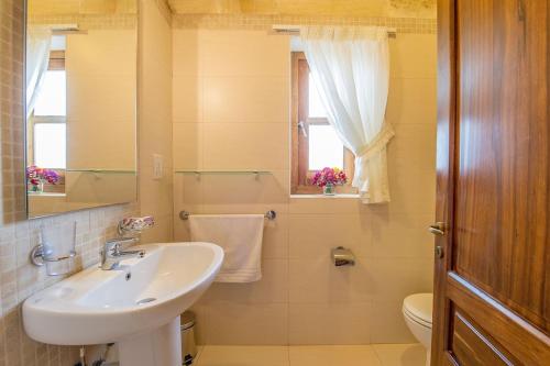 La salle de bains est pourvue d'un lavabo, de toilettes et d'un miroir. dans l'établissement The Hamlet 3 Holiday Home, à Għasri