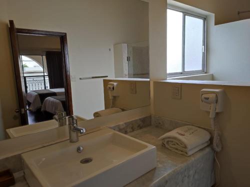 a bathroom with a sink and a mirror at Hotel Sand´s San Luis in San Luis Potosí