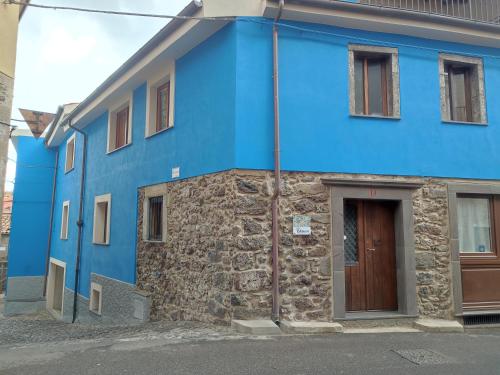 a blue house with a stone wall at Deiana in Santu Lussurgiu