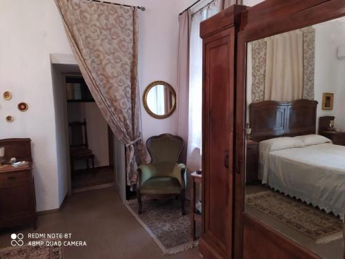 a bedroom with a bed and a chair and a mirror at Palazzo Vertemate Traona in Traona