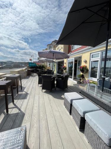 a patio with tables and chairs and an umbrella at Mariners Hotel in Seaton