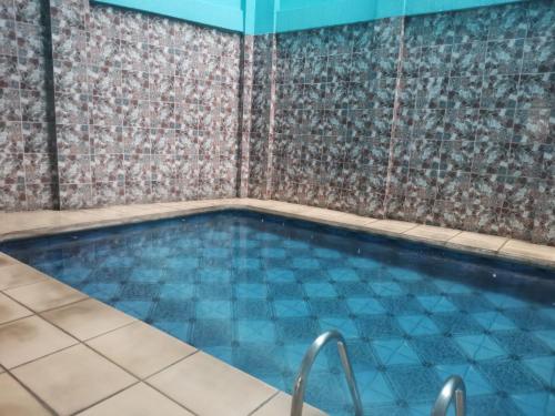 a swimming pool in a room with a tile wall at Hotel La Guaria in Liberia