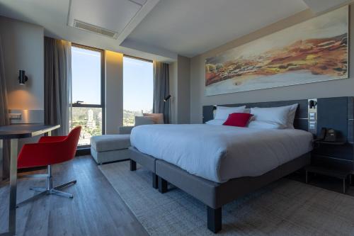 a hotel room with a large bed and a desk and a table at Novotel Vina del Mar in Viña del Mar