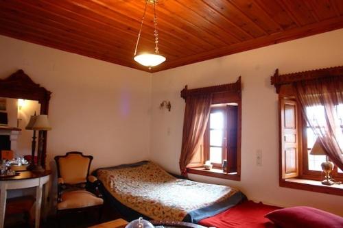a bedroom with a bed and two windows at Traditional Rooms karaouli in Papigko