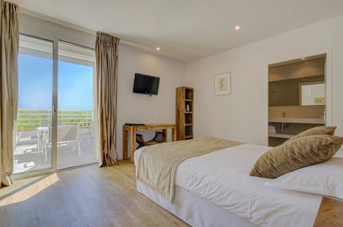 a bedroom with a large bed and a balcony at Le Cottage - Hotel & Spa in Argelès-sur-Mer