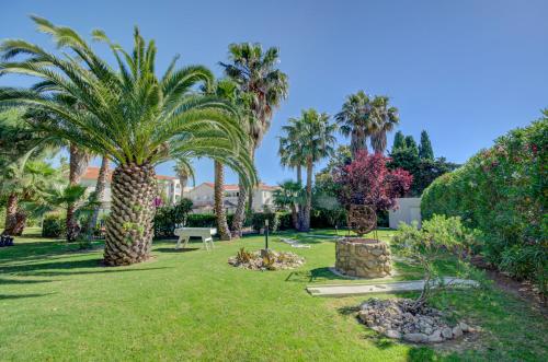 a park with palm trees and grass and bushes at Le Cottage - Hotel & Spa in Argelès-sur-Mer