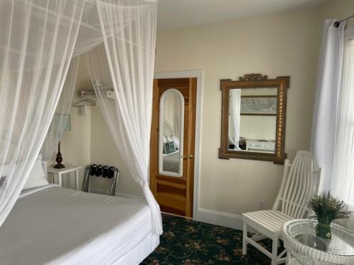 a bedroom with a bed and a chair and a mirror at Hotel Macomber in Cape May