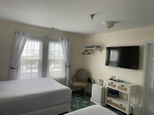 a bedroom with a bed and a flat screen tv at Hotel Macomber in Cape May