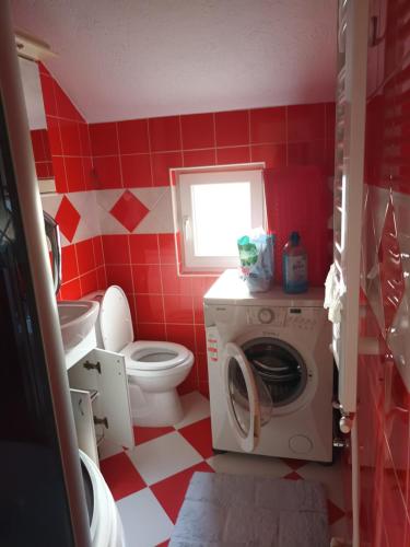 a red and white bathroom with a toilet and a washing machine at Sve u jednom in Bijelo Polje