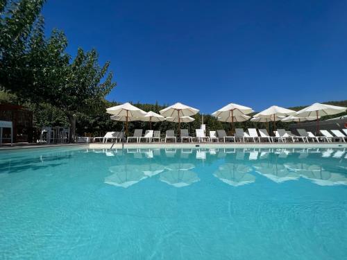 a large swimming pool with umbrellas and tables and chairs at Hotel Rosaleda del Mijares in Montanejos