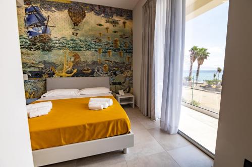 a bedroom with a yellow bed with a painting on the wall at MARINO WELLNESS in Alì Terme