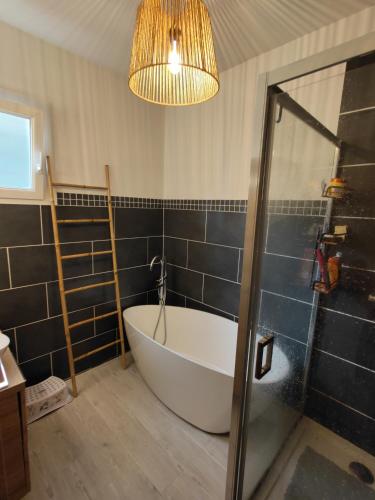 La salle de bains est pourvue d'une baignoire et d'un lustre. dans l'établissement maison landaise à proximité de la plage et centre, à Biscarrosse-Plage