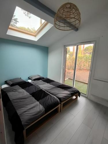 une chambre avec un lit et une grande fenêtre dans l'établissement maison landaise à proximité de la plage et centre, à Biscarrosse-Plage