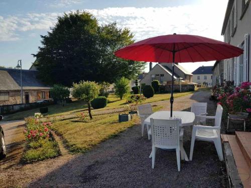 a table and chairs with a red umbrella at Maison de maître à 2 pas du lac des Settons in Montsauche