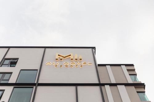 a building with a sign on the side of it at Mii Hotel Srinakarin in Bangna