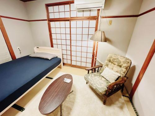 ein Schlafzimmer mit einem Bett, einem Stuhl und einem Tisch in der Unterkunft Sara in Kagoshima