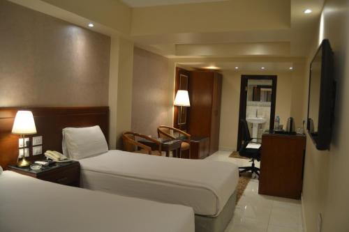 ミニヤーにあるOmar El Khayam Al Minya Hotelのベッド2台と机があるホテルの部屋