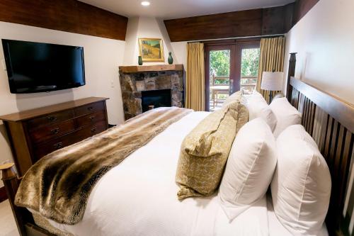 a bedroom with a bed with white pillows and a television at Deluxe King Room with Fireplace Hotel Room in Park City