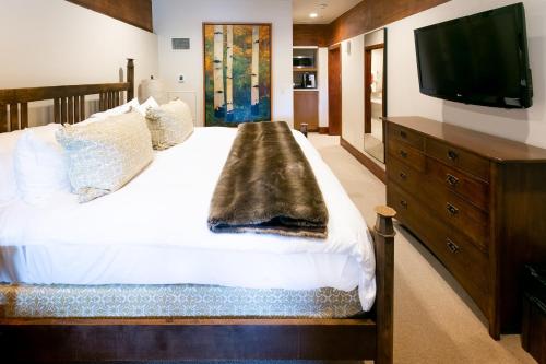 a bedroom with a large bed with a television on the wall at Deluxe King Room with Fireplace Hotel Room in Park City
