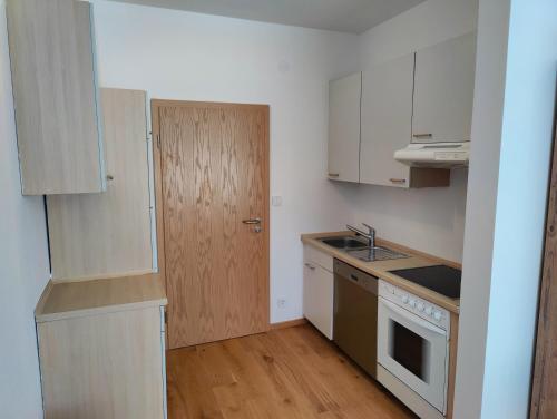 a small kitchen with white cabinets and a wooden door at Ferien vom Ich, Bayerischer Wald, Hotel & Restaurant in Neukirchen
