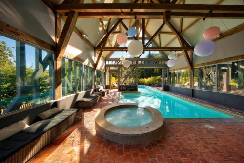 an indoor swimming pool with a large building at Hotel Du Grand Cerf & Spa in Lyons-la-Forêt