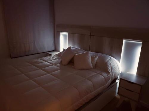 a bedroom with a white bed with two pillows at Departamento en Refinería Alto Rosario III in Rosario