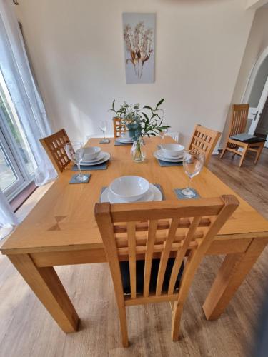 a wooden table with chairs and plates and glasses at Contractors Home from Home in South Benfleet