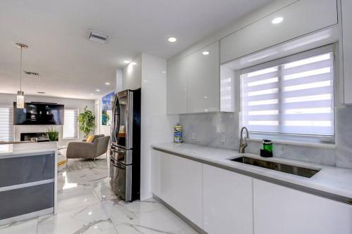 a white kitchen with a sink and a refrigerator at Miami House with Hot Pool-spa & Pool table L48 in Hialeah