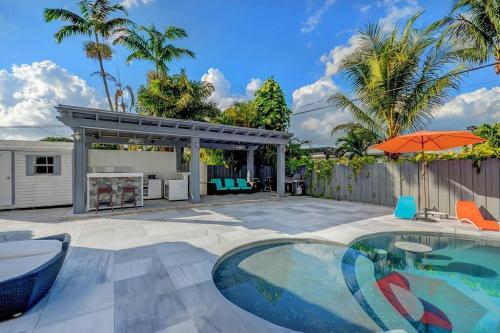 eine Terrasse mit Pool und Sonnenschirm in der Unterkunft Miami House with Hot Pool-spa & Pool table L48 in Hialeah
