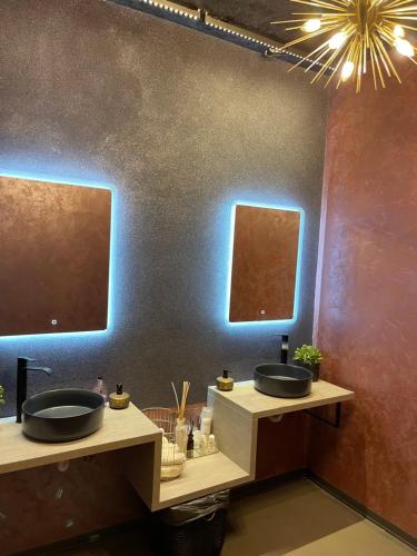 two sinks in a bathroom with two mirrors at Pensiunea Casa Buna in Gîrbova