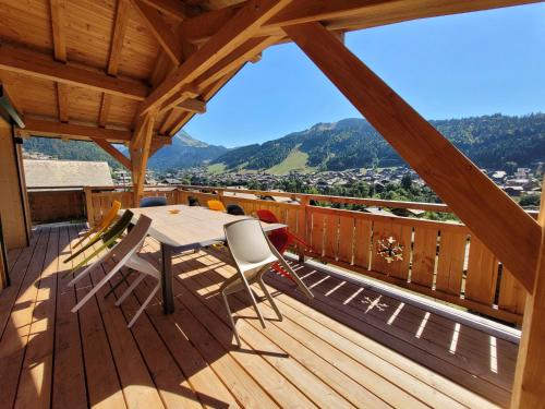 una terraza de madera con mesa y sillas. en Julianna , appartements avec services gratuits en Morzine