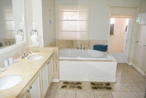 a white bathroom with two sinks and a tub at The Bliss in Gros Islet