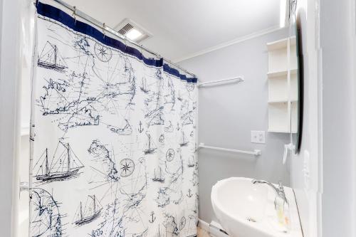 La salle de bains est pourvue d'un rideau de douche et de dessins de bateaux. dans l'établissement SeaWind Guest Studio, à Nauset Heights