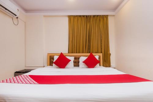 a bedroom with a large bed with red pillows at Capital O Orbit Inn Near Infiniti Mall in Mumbai