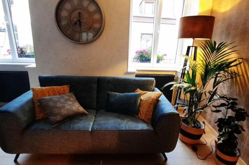 eine Couch in einem Wohnzimmer mit einer Uhr an der Wand in der Unterkunft Le Relais des Imprimeurs in Bouillon