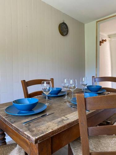- une table en bois avec des assiettes, des bols et des verres à vin dans l'établissement Logement Pays des Écrins, à La Roche-de-Rame