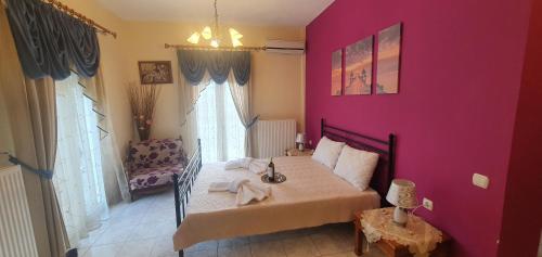 a bedroom with a pink wall with a bed and a chair at panos rooms in Kalabaka