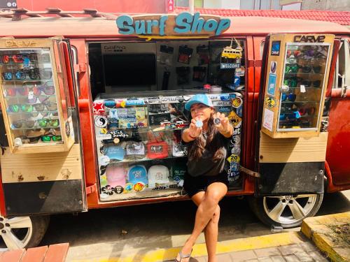 a woman sitting in front of a surf shop at Surf hostel My Friends in Huanchaco