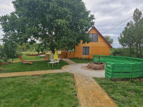 une maison avec un arbre et une aire de jeux dans l'établissement Hobby Vendégház, à Kiskunmajsa