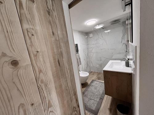 a bathroom with a white sink and a toilet at Loft Malga Laghetto in Lavarone