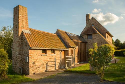 an old brick house with a chimney and a gate at Hof ter Sysen in Loppem